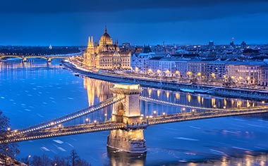 A view over the Danube River towards the Chain Bridge and Parliament Building in Budapest at dusk during winter